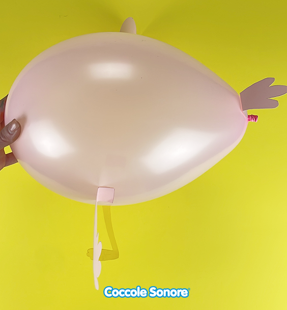 Gonfiamo il secondo palloncino con più forza cercando di ottenere una forma più allungata, poi con il biadesivo attacchiamo tutti gli elementi precedentemente creati come in foto.